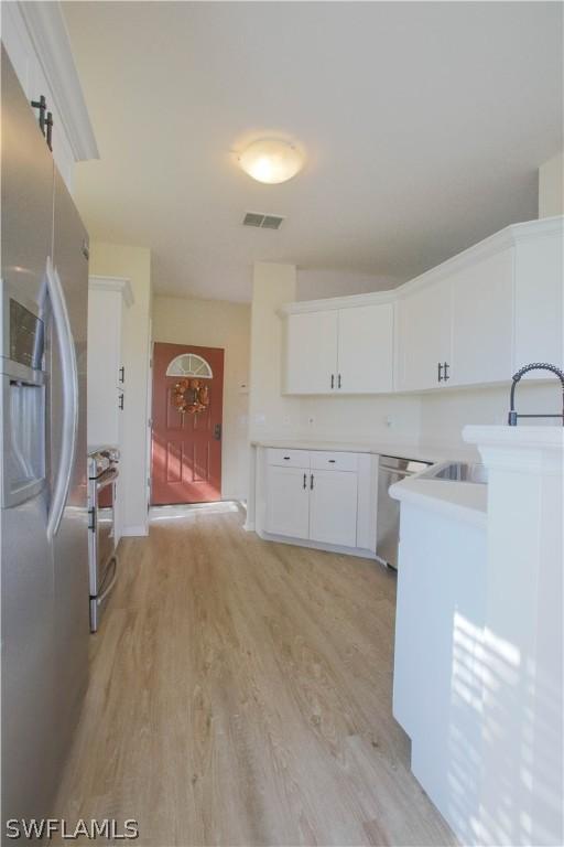 kitchen featuring light hardwood / wood-style floors, appliances with stainless steel finishes, a barn door, and white cabinets