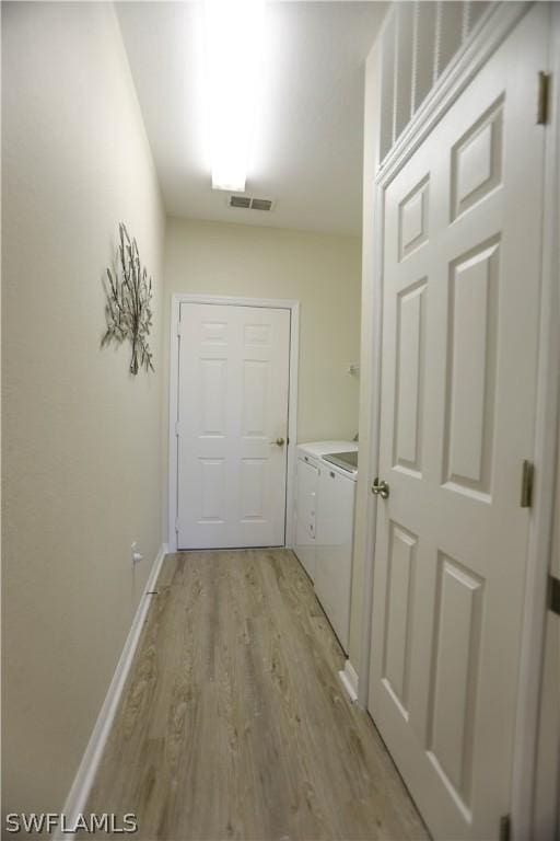 corridor with washer and dryer and light hardwood / wood-style floors