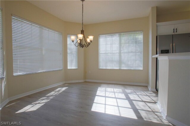 unfurnished dining area with a notable chandelier and light wood-type flooring