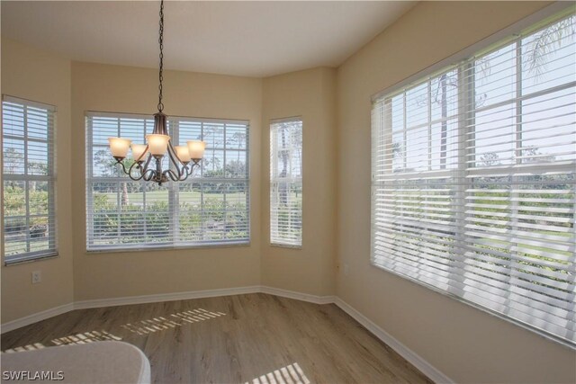 unfurnished dining area with a notable chandelier, a healthy amount of sunlight, and hardwood / wood-style floors