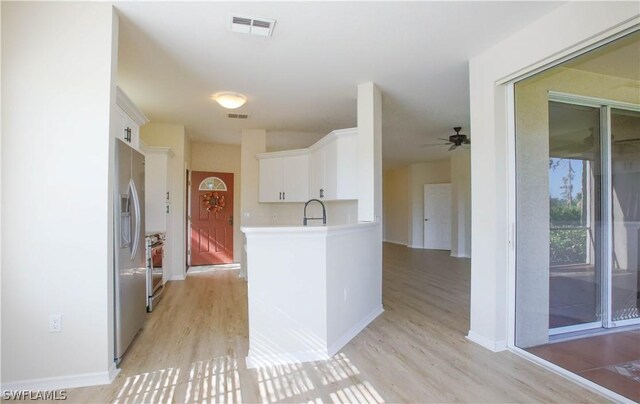 kitchen with white cabinetry, light hardwood / wood-style flooring, appliances with stainless steel finishes, and kitchen peninsula