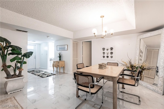 dining space with an inviting chandelier, tile patterned flooring, a raised ceiling, and a textured ceiling