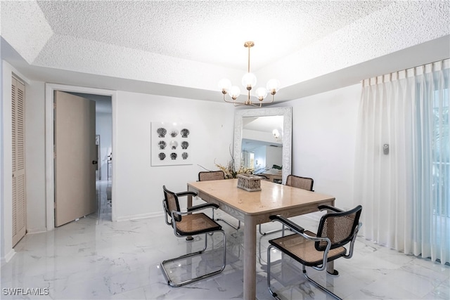 tiled dining area featuring an inviting chandelier, a textured ceiling, and a tray ceiling