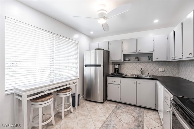 kitchen featuring light tile patterned flooring, tasteful backsplash, ceiling fan, sink, and stainless steel refrigerator