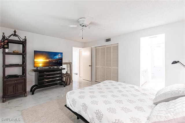 tiled bedroom with ensuite bathroom, ceiling fan, and a closet