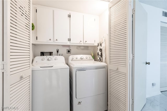 laundry room with independent washer and dryer, cabinets, and light tile patterned floors