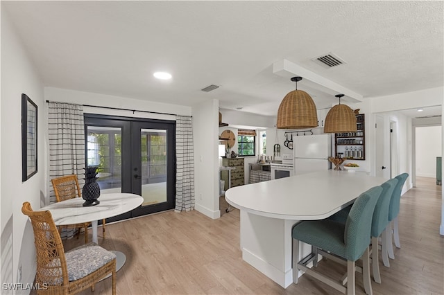 kitchen with decorative light fixtures, white refrigerator, french doors, light hardwood / wood-style flooring, and a wealth of natural light