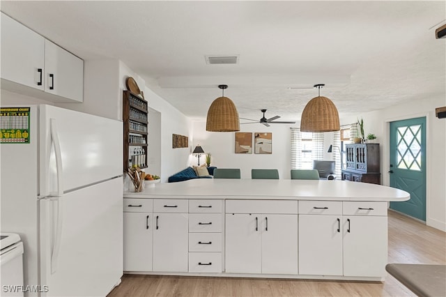 kitchen with white refrigerator, hanging light fixtures, white cabinets, light wood-type flooring, and kitchen peninsula