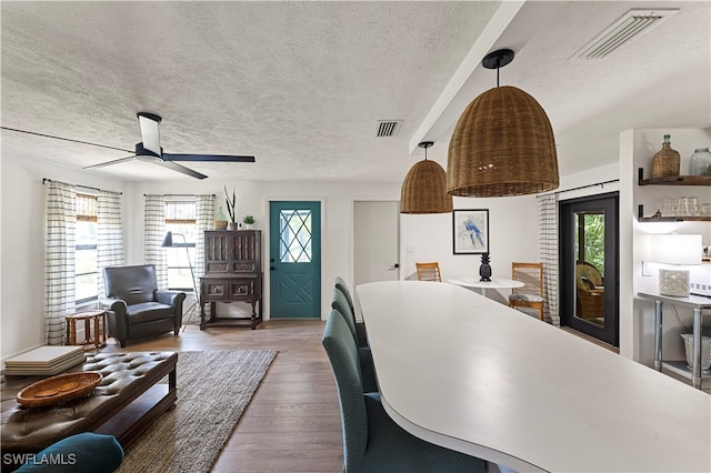 living room with a textured ceiling, ceiling fan, and wood-type flooring