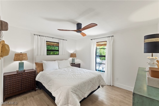 bedroom featuring ceiling fan, multiple windows, and light hardwood / wood-style flooring