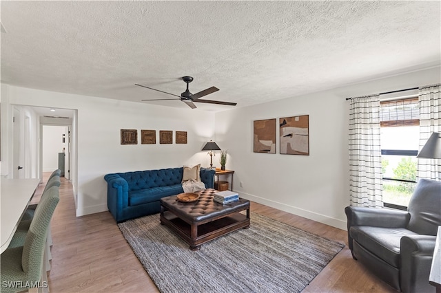 living room with hardwood / wood-style flooring, a textured ceiling, and ceiling fan