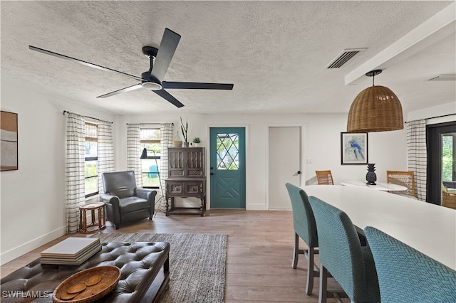 living room with ceiling fan, light hardwood / wood-style floors, and a textured ceiling