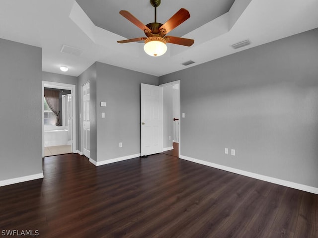 unfurnished room featuring a raised ceiling, ceiling fan, and dark hardwood / wood-style flooring