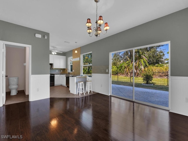 unfurnished living room with hardwood / wood-style floors, ceiling fan with notable chandelier, and sink