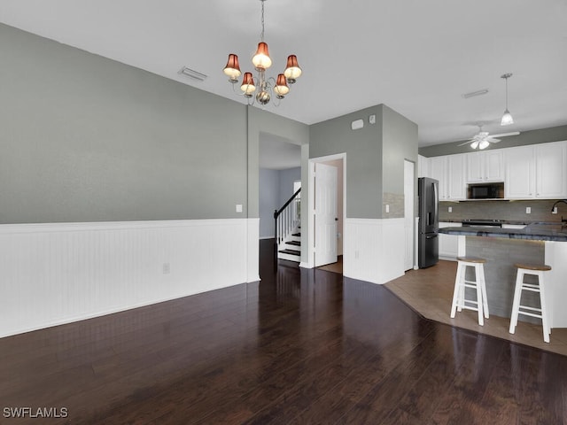 kitchen with kitchen peninsula, stainless steel refrigerator with ice dispenser, a breakfast bar, dark wood-type flooring, and white cabinetry