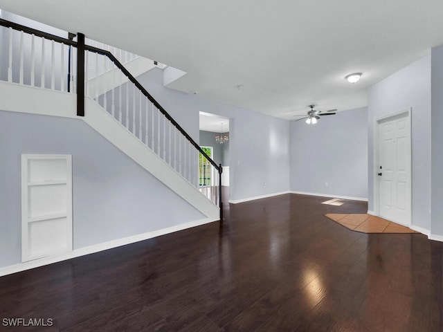 unfurnished living room featuring built in shelves, wood-type flooring, and ceiling fan with notable chandelier