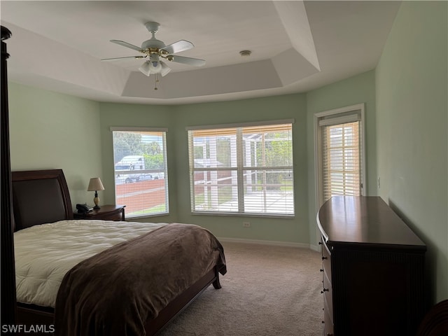 carpeted bedroom featuring ceiling fan and a tray ceiling