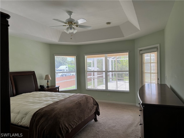 bedroom with carpet floors, ceiling fan, and a raised ceiling