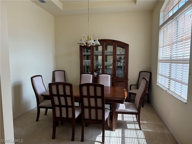 carpeted dining room with a raised ceiling and a notable chandelier