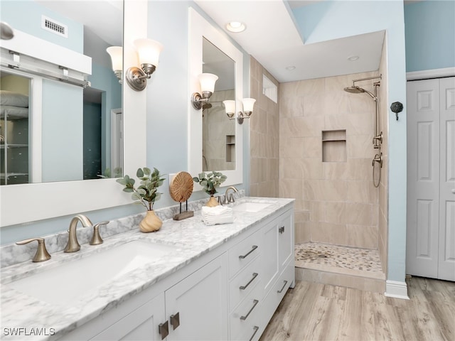 bathroom featuring vanity, wood-type flooring, and tiled shower