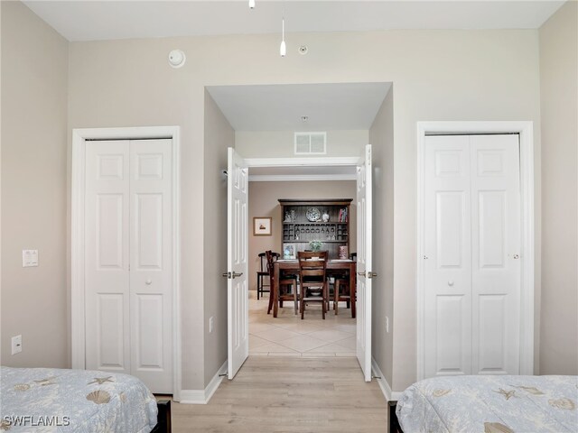 bedroom with light hardwood / wood-style flooring and multiple closets