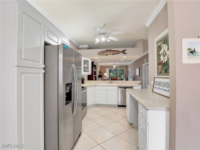 kitchen with sink, light tile patterned floors, ornamental molding, stainless steel appliances, and white cabinets