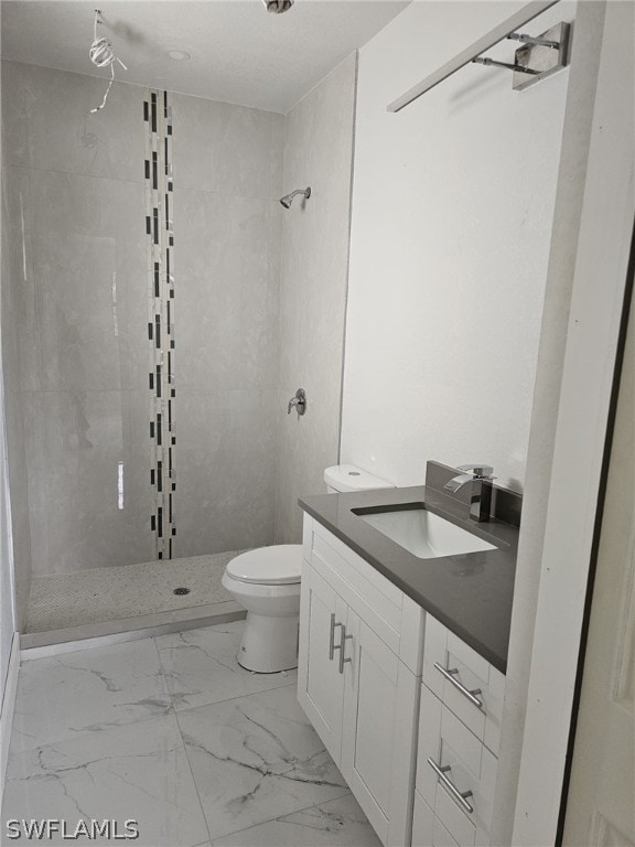 bathroom with tiled shower, vanity, and toilet