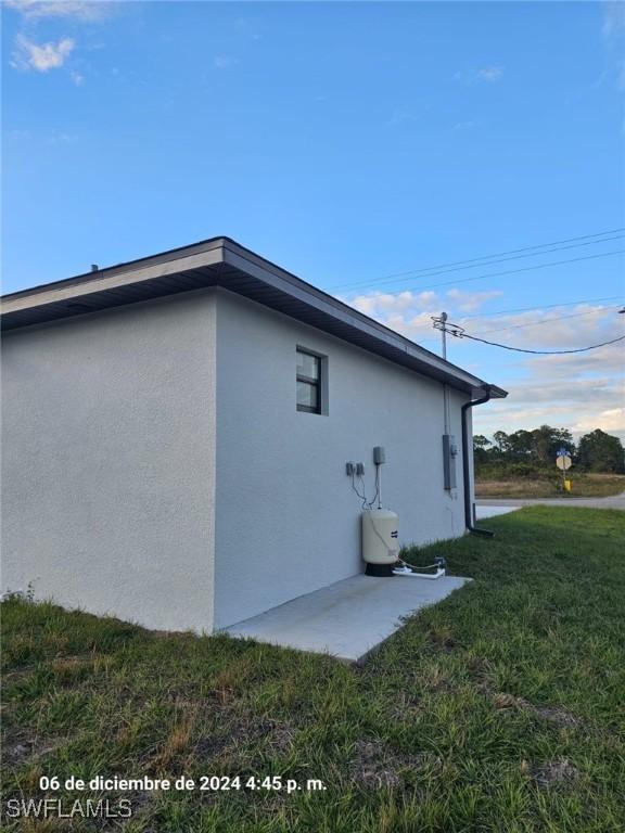 view of side of home with a patio area and a lawn