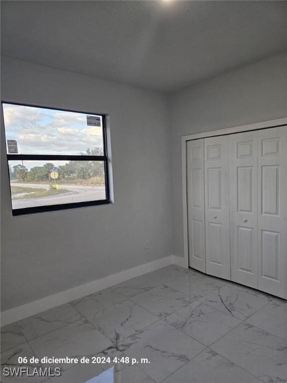 2801 48th St W, Lehigh Acres, FL 33971 - unfurnished bedroom with baseboards, marble finish floor, and a closet