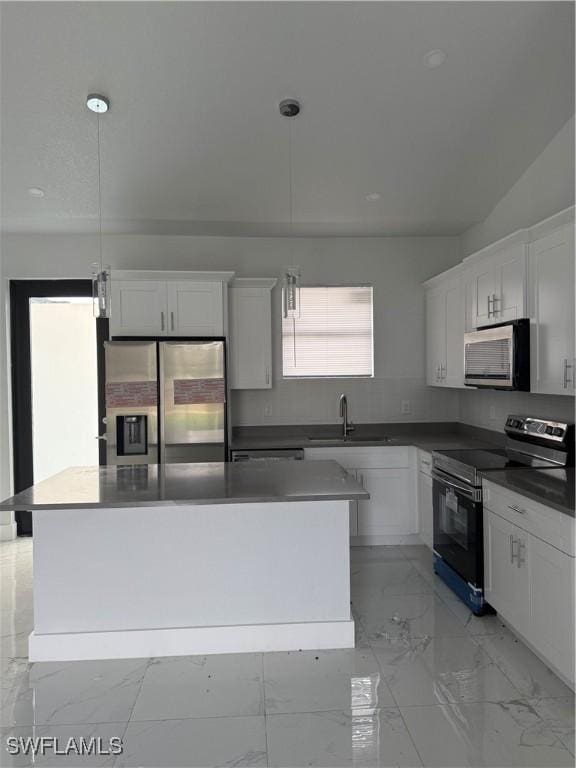 kitchen featuring stainless steel appliances, a kitchen island, sink, decorative light fixtures, and white cabinetry