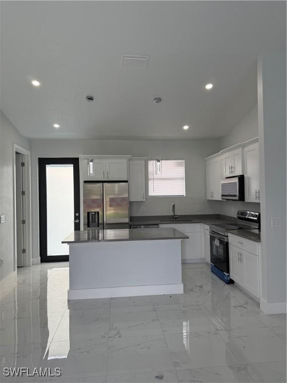 kitchen featuring white cabinetry, a center island, sink, and appliances with stainless steel finishes