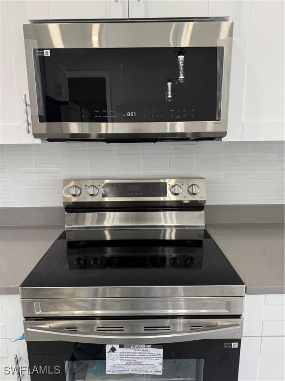 details featuring decorative backsplash, white cabinetry, and appliances with stainless steel finishes