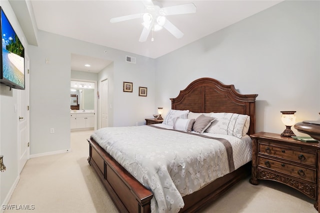 bedroom with ensuite bathroom, light colored carpet, and ceiling fan