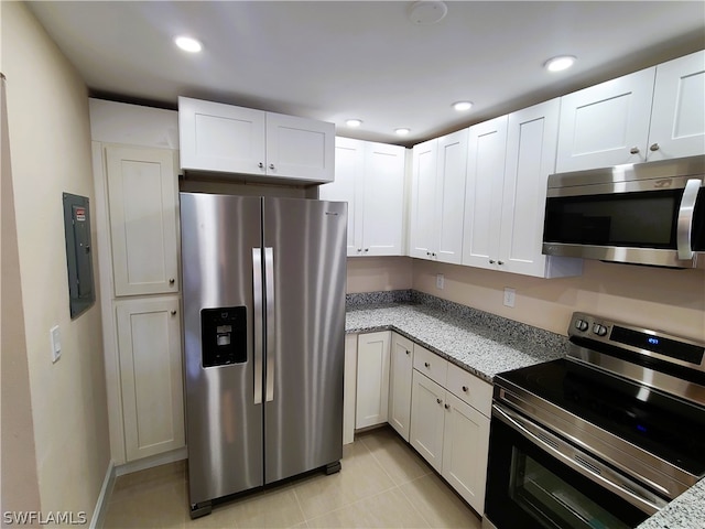 kitchen with white cabinetry, light stone countertops, stainless steel appliances, and light tile patterned floors