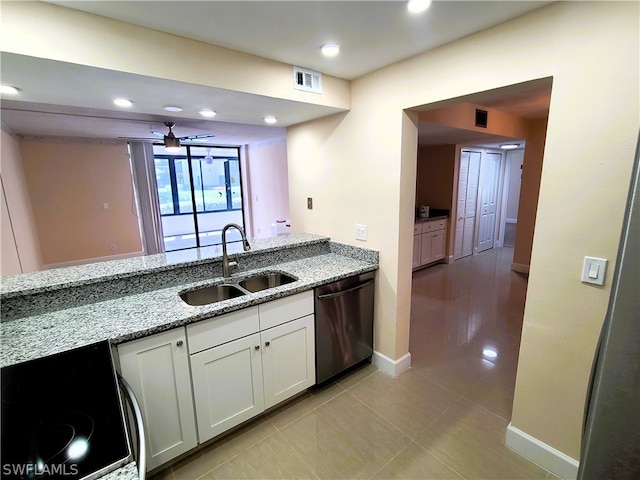 kitchen with stainless steel dishwasher, light tile patterned flooring, white cabinets, sink, and light stone countertops