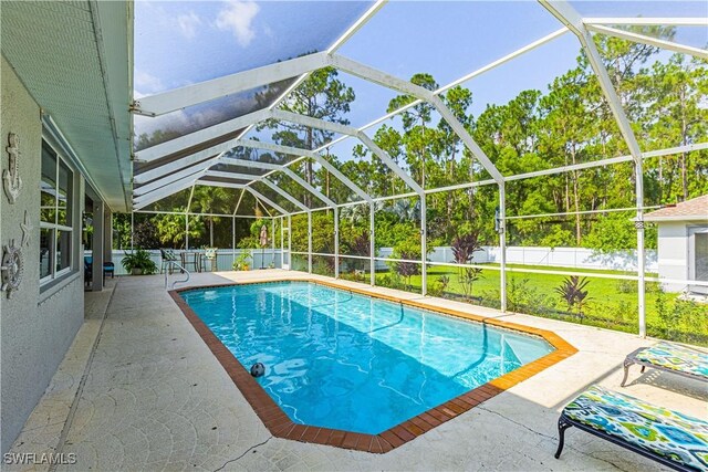 view of swimming pool featuring a lawn, a patio, and glass enclosure