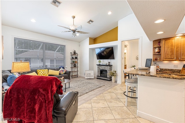 living room with ceiling fan, vaulted ceiling, and light tile patterned floors