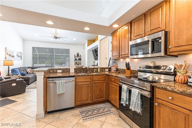 kitchen with stainless steel appliances, dark stone counters, ceiling fan, sink, and light tile patterned flooring