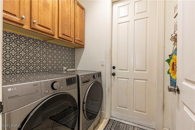 laundry room with tile patterned flooring, washer and clothes dryer, and cabinets