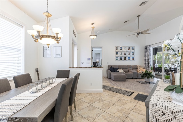 tiled dining area featuring ceiling fan with notable chandelier, vaulted ceiling, and plenty of natural light