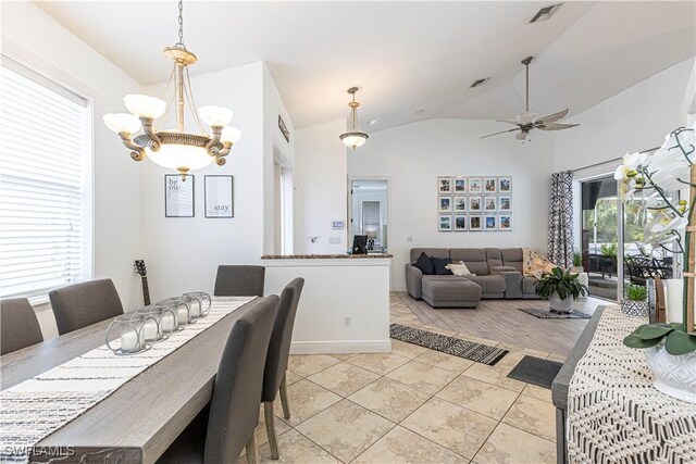 dining area featuring ceiling fan with notable chandelier, lofted ceiling, a wealth of natural light, and light tile patterned floors