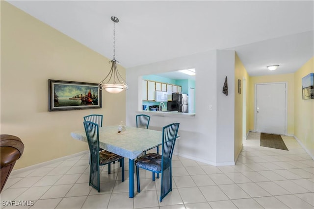 dining area featuring lofted ceiling, light tile patterned flooring, and baseboards