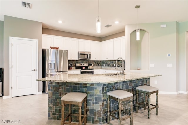 kitchen with white cabinetry, stainless steel appliances, a breakfast bar area, and sink