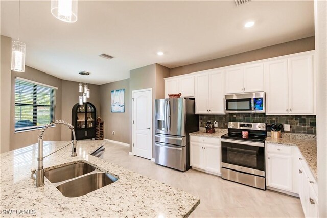 kitchen with light tile patterned flooring, hanging light fixtures, decorative backsplash, sink, and appliances with stainless steel finishes