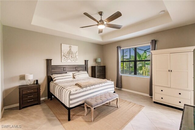 bedroom featuring a raised ceiling, light tile patterned floors, and ceiling fan