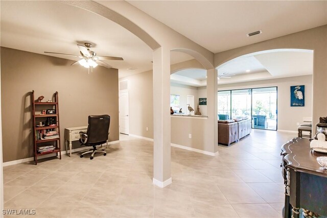 office area with a tray ceiling, ceiling fan, and light tile patterned floors