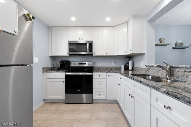 kitchen with white cabinetry, sink, stainless steel appliances, and dark stone countertops