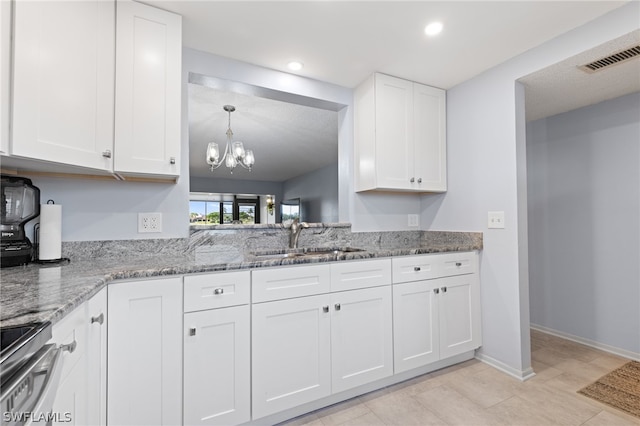 kitchen with sink, stainless steel range with electric cooktop, white cabinetry, an inviting chandelier, and light stone countertops