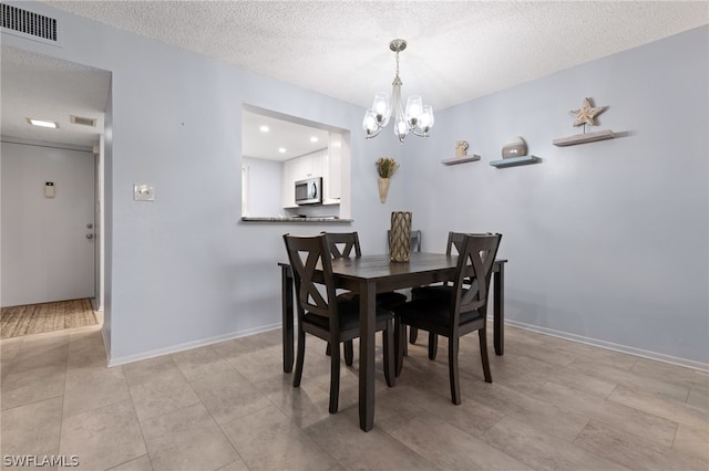 dining area featuring light tile patterned flooring, a textured ceiling, and a notable chandelier