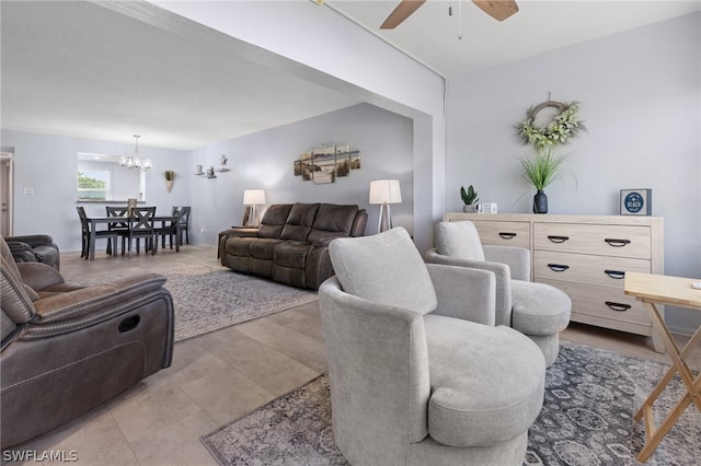 tiled living room with ceiling fan with notable chandelier